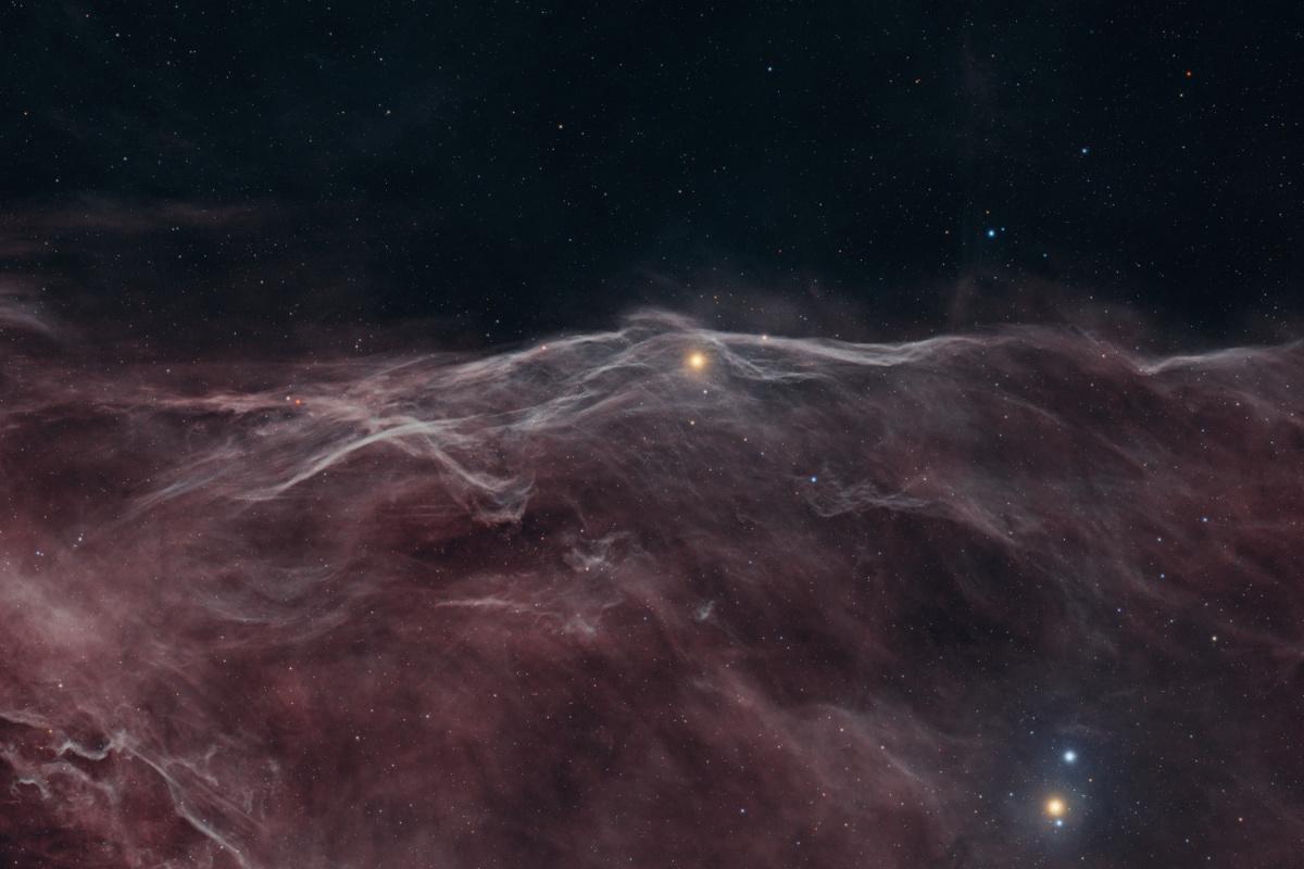 The same field in the HSS palette: a deep brick-red cloud filling the lower two thirds of the frame, its ridge and filaments picked out in pale grey, under a dark and thinly starred sky.